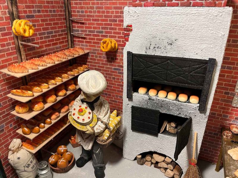 Historische Bäckerei mit Broten und Backwaren auf Regalen sowie Backofen